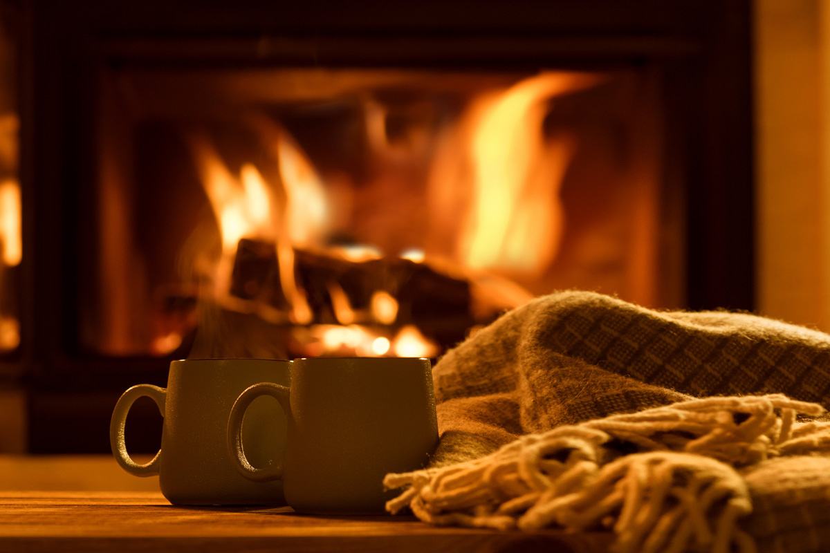 Steam from a cups with a hot cocoa on the fireplace background.