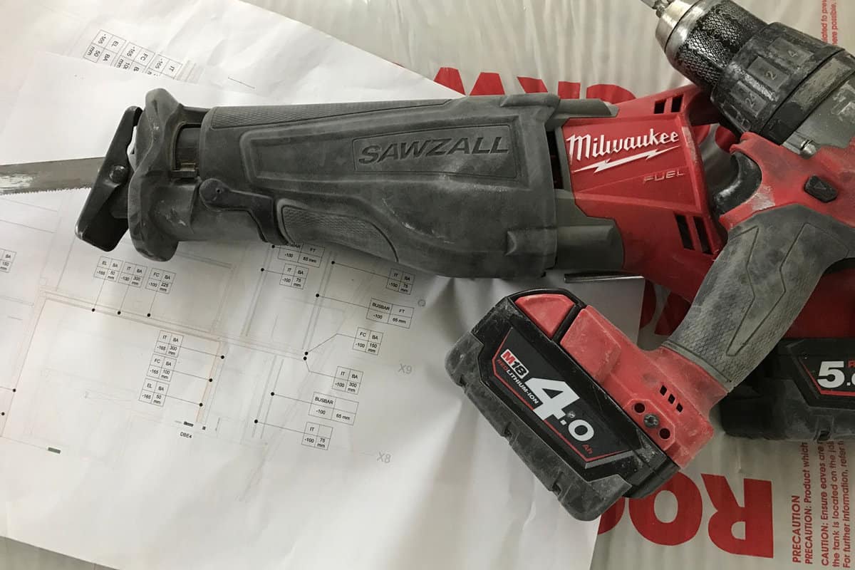 Trade cordless power drill and saw over electrical technical drawings