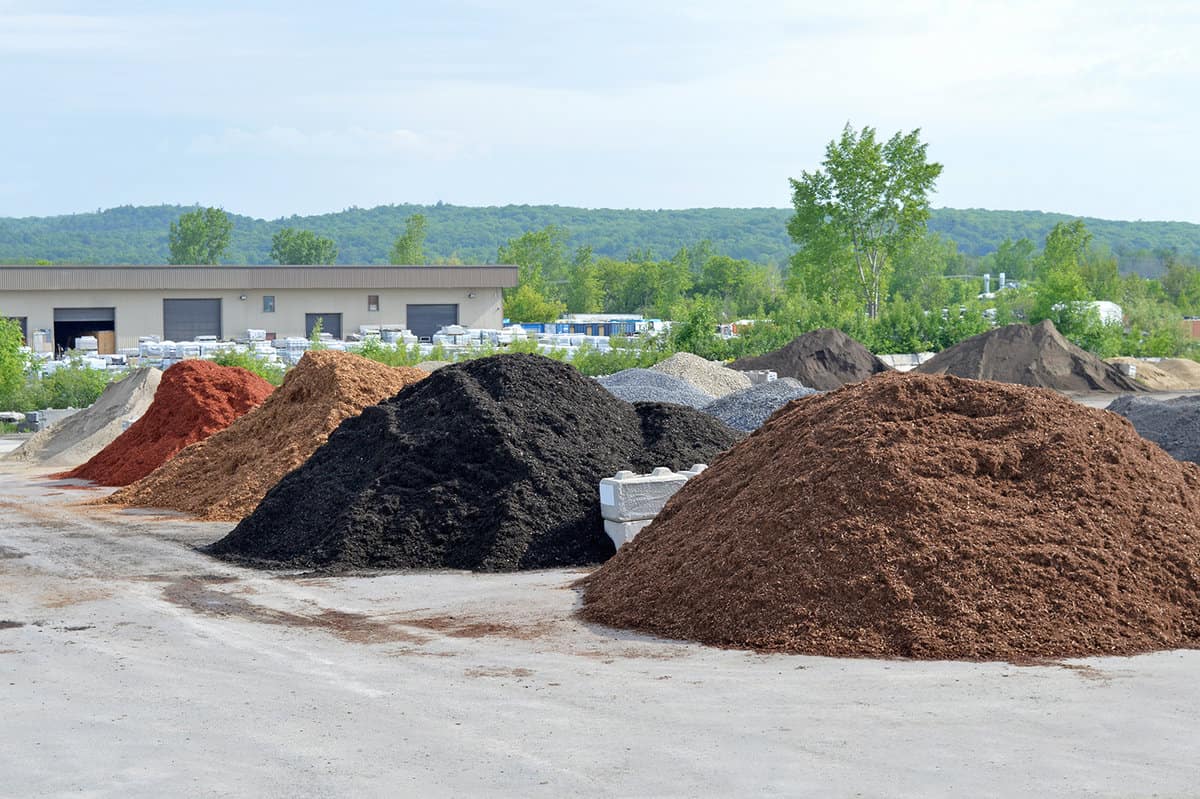 Various stone and cedar mulch piles separated into various types for packaging in the warehouse
