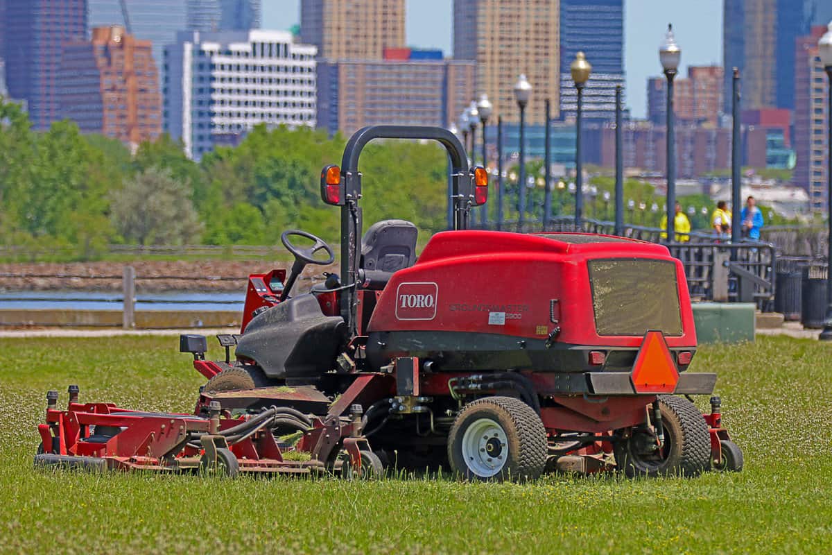 A Toro Groundmaster 5900 ride-on lawnmower with a number of skyscrapers visible in the background. This mower is loaded with productivity-boosting
