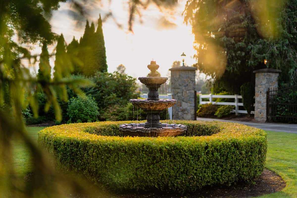 A gorgeous stone fountain with grass hedges surrounding it