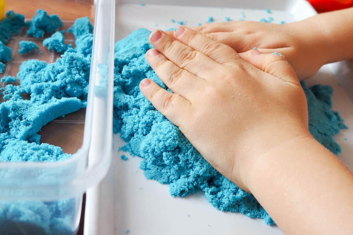 Little kid playing with blue playing sand