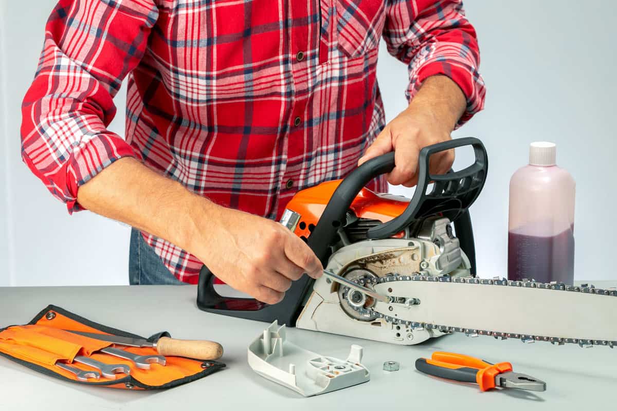 Man repairing chainsaw in a workshop. Small business concept. 