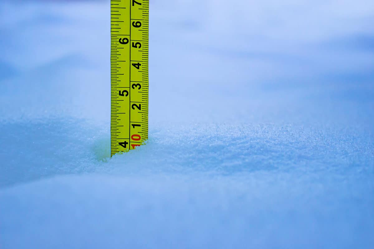 Measuring the snow depth with yellow ruler 10 Centimeters