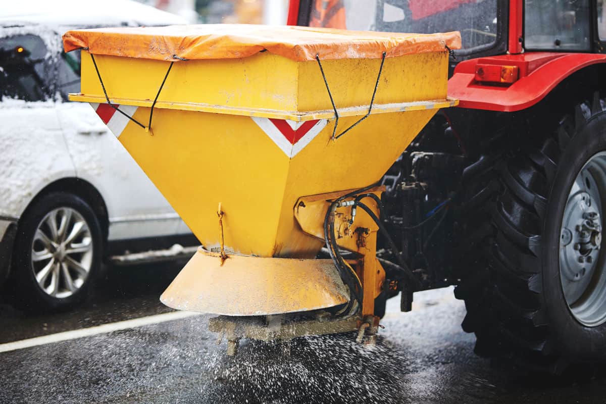 Tractor with mounted salt spreader, road maintenance winter gritter vehicle