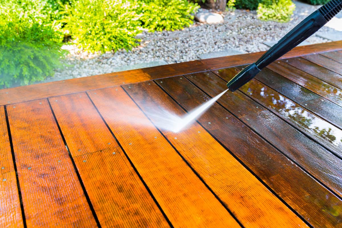Using a power sprayer to clean the wooden deck
