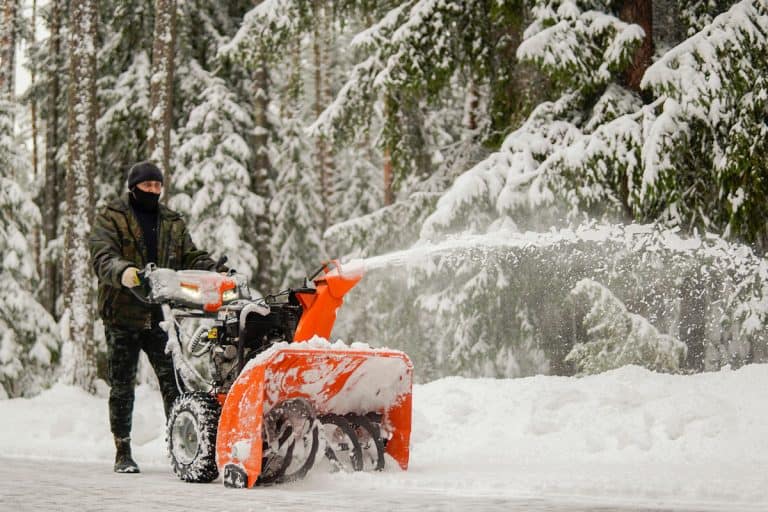 a man removes snow with a snowblower on the background of a snowy forest, How To Attach A Snowblower To A Lawn Tractor
