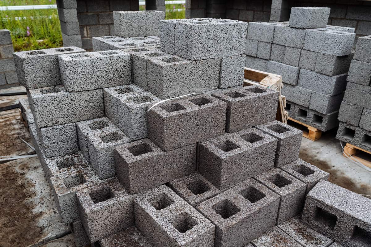 cinder blocks of gray concrete are neatly stacked in a pile, slender rows of bricks