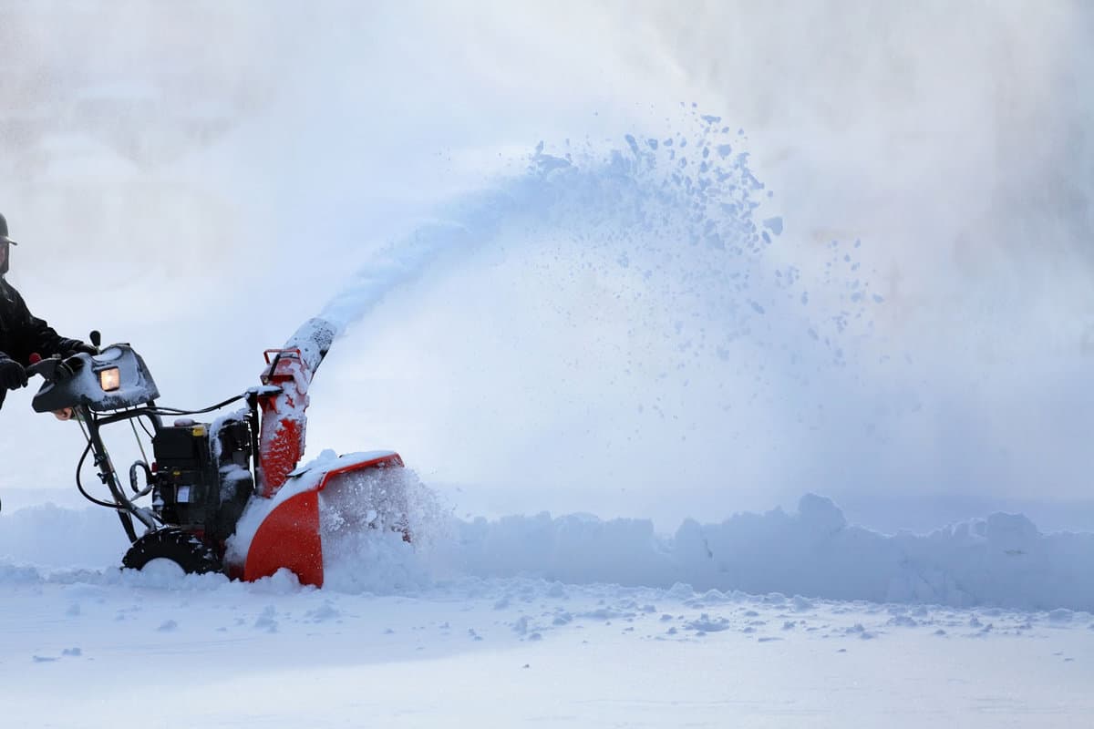 Man working with snow blower after winter storm in city 