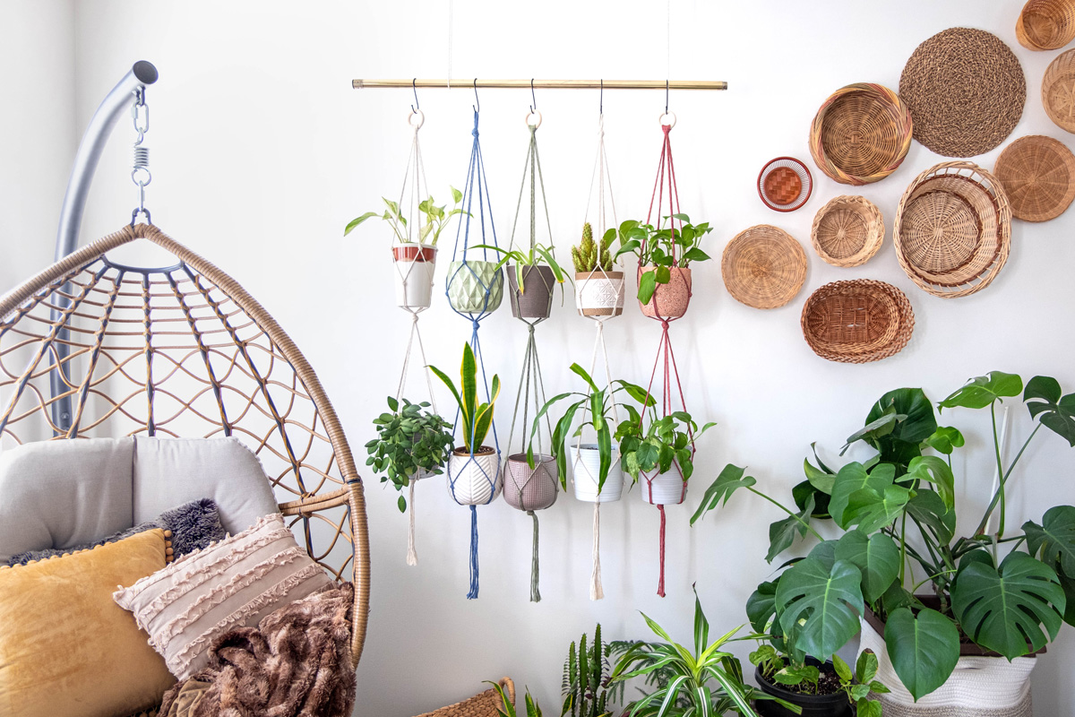 Multiple-macrame-plant-hangers-with-indoor-houseplants-and-pot-planters-are-hanging-from-a-metal-pole.
