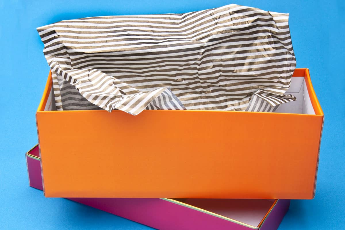 Orange and pink fancy gift box opened with striped tissue paper