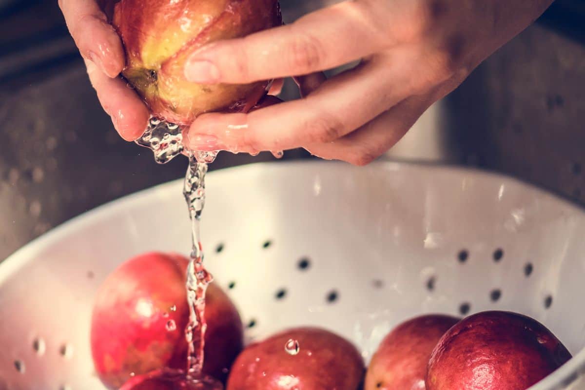 A person washing pomegranate under running water food photography idea