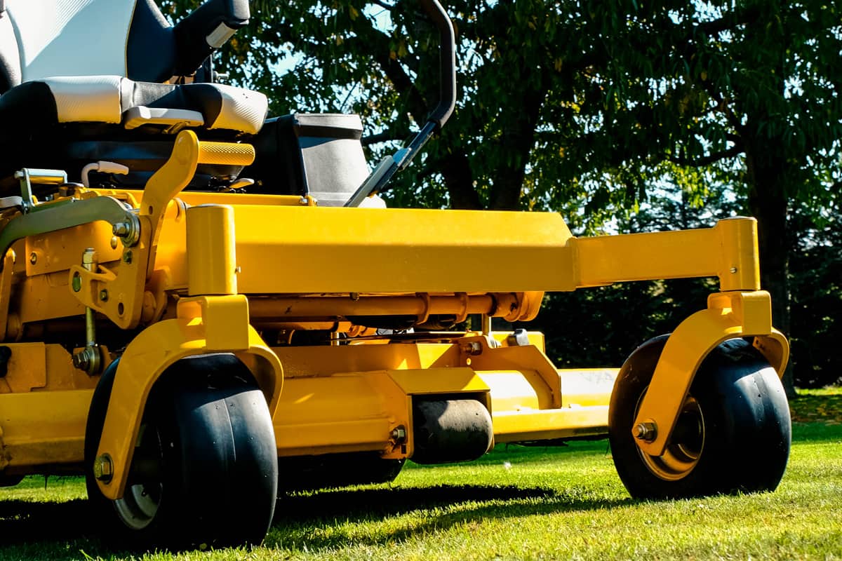 Yellow zero-turn mower parked in the middle of the green grass field