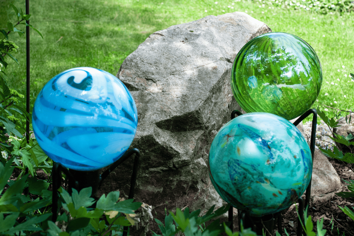 3 gazing balls in a garden in front of a rock