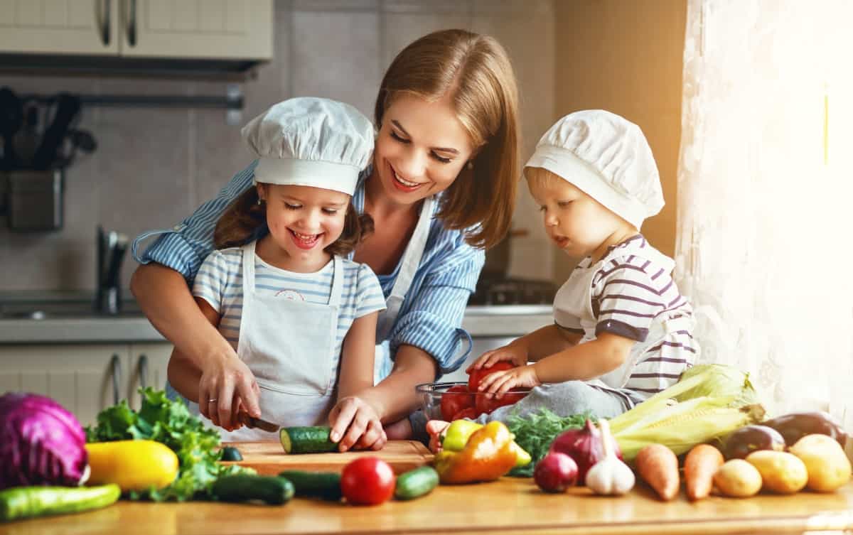Healthy eating. Happy family mother and children prepares vegetable salad in kitchen