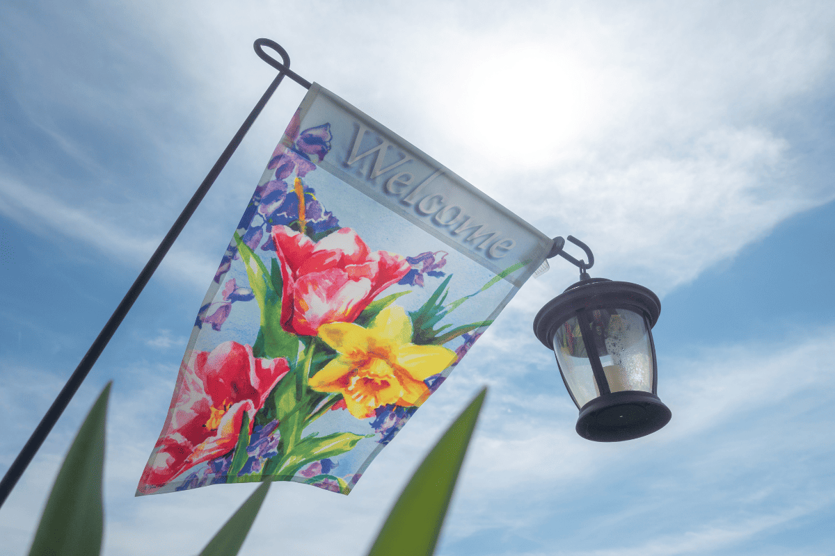 Welcome garden flag and colonial lantern against blue sky