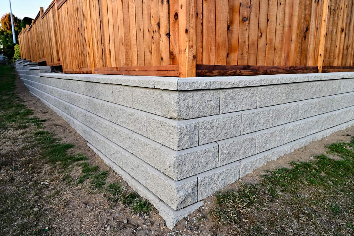 block wall corner with wooden fence, concrete block retaining wall, gray concrete blocks, wall fence