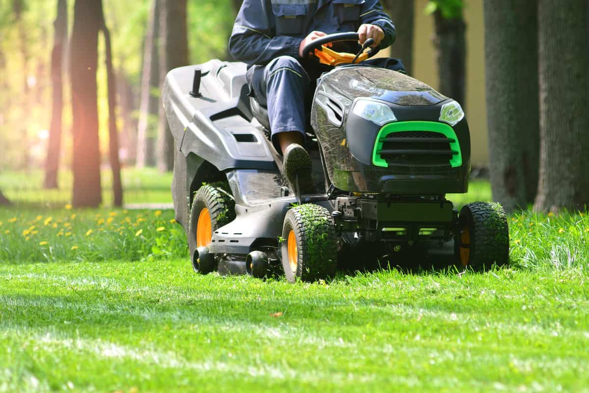 A gardener using a riding lawn mower at gulf course