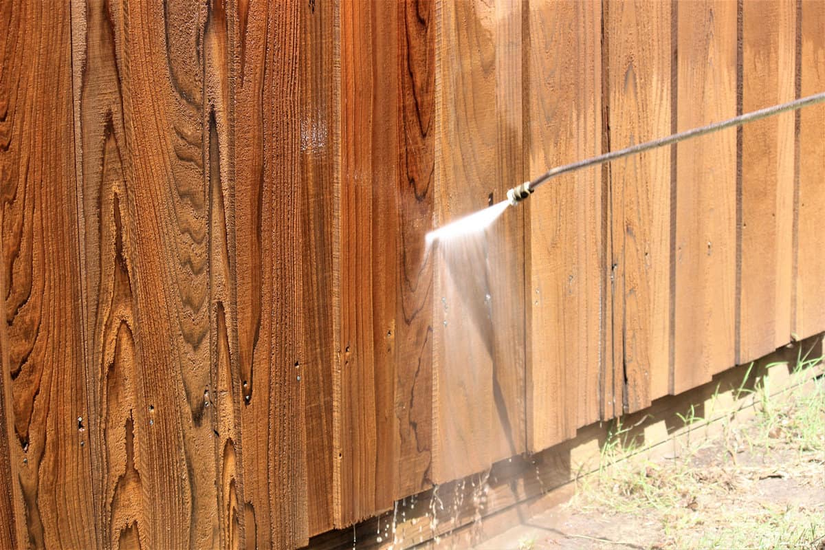 Power spraying a fence to clean it