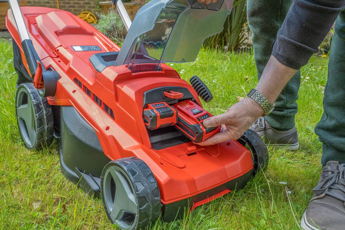 Gardener placing new battery to the lawn mower
