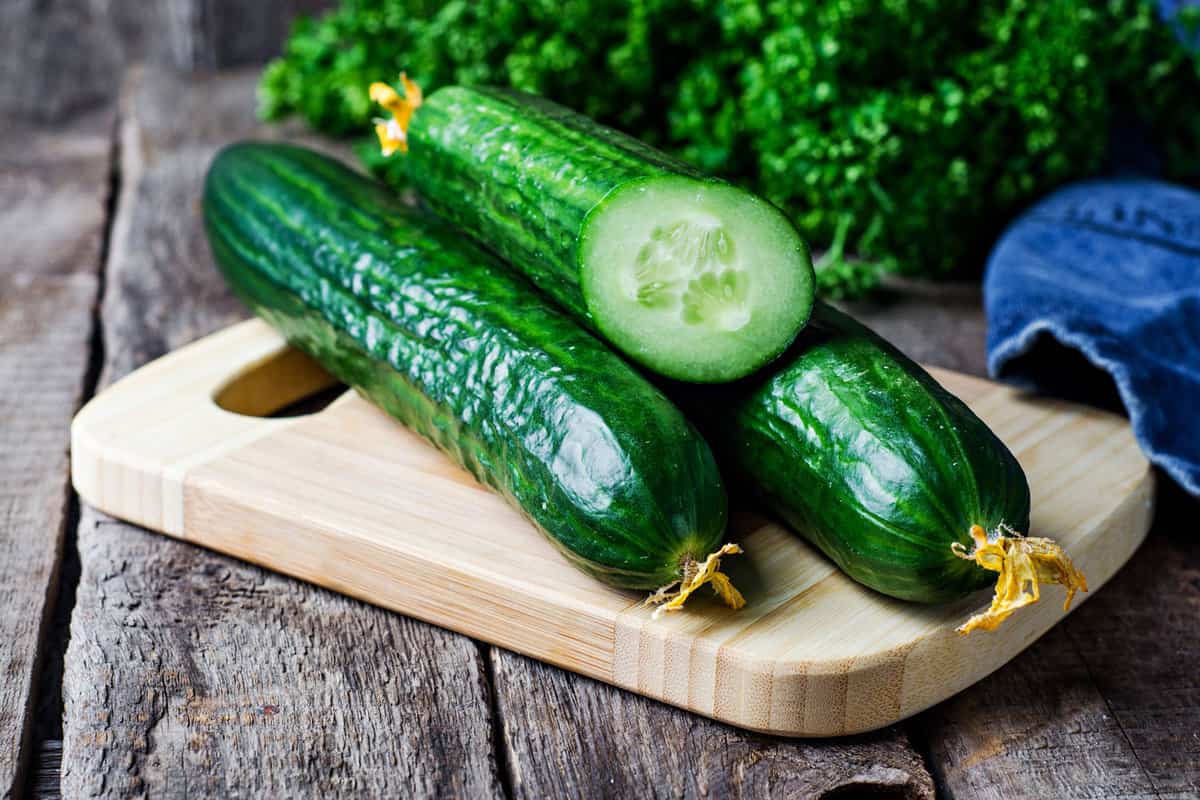 Three cucumbers on top of a chhopping board