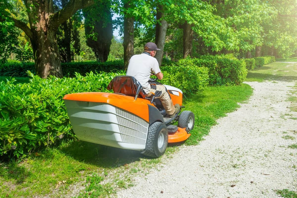 Man using his riding lawn mower to mow the backyard lawn