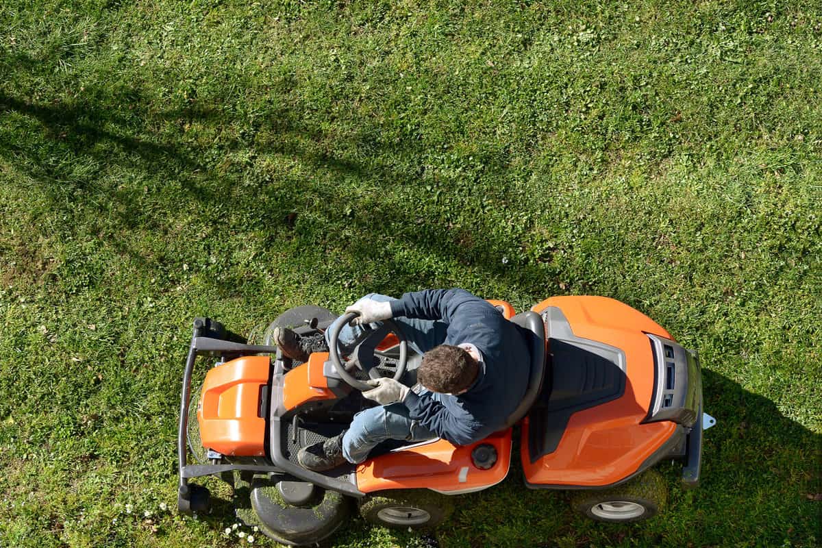 Aerial photo of a man mowing his lawn with a riding lawnmower
