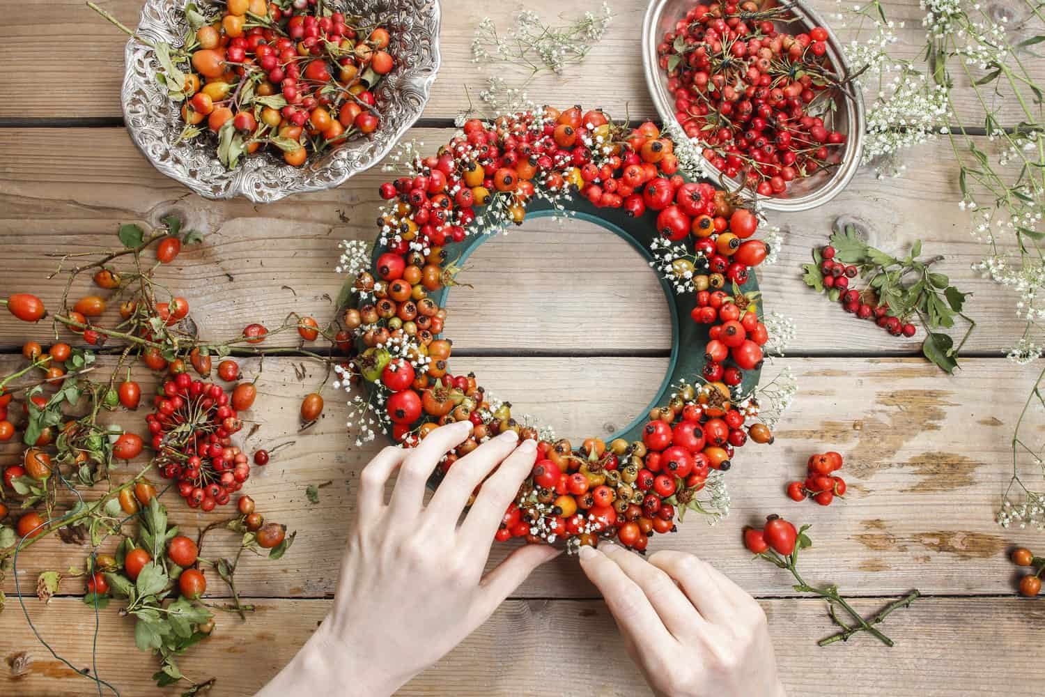 woman making rose hip and hawthorn wreath