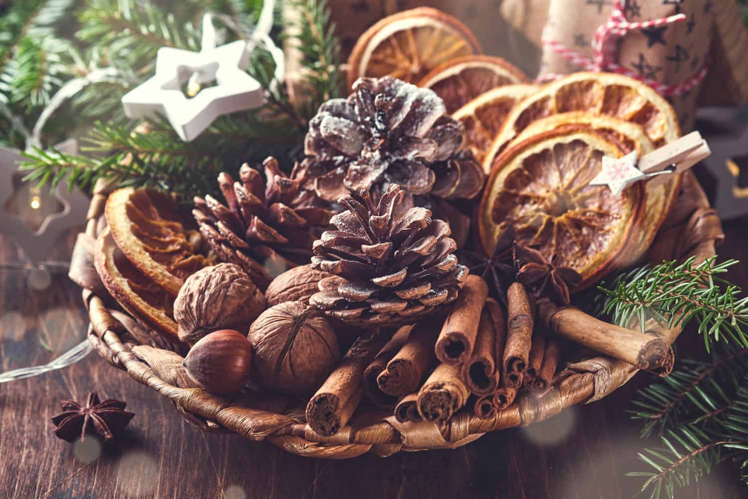Dry orange, star anise, cinnamon, pine cones and fir tree in rustic plate on wooden table
