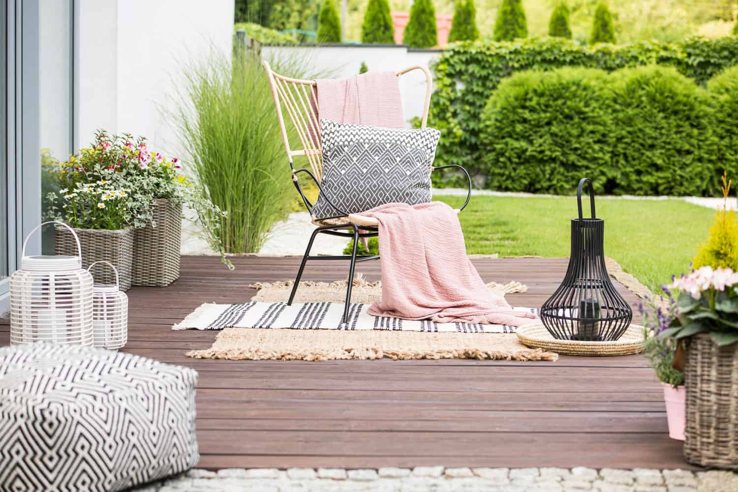A chair on the backyard porch with a pink blankets and pillows for relaxation
