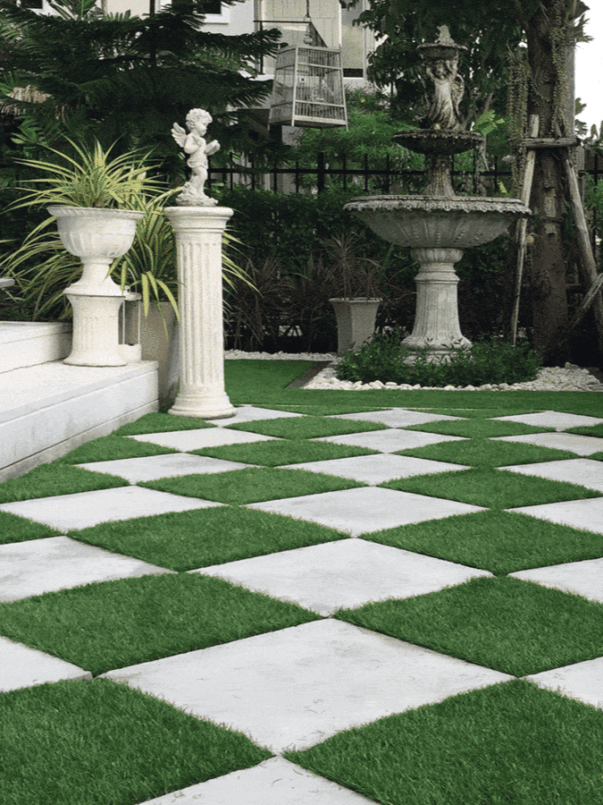 A classic checkerboard garden path of white marble squares and vibrant green grass is lined with an ornate statue, a traditional urn, and an elegant tiered fountain, contributing to the formal and manicured landscape design ar 3:4