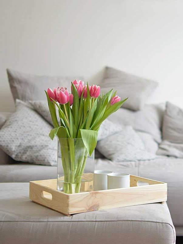 Pink tulips in glass vase with sofa on the living room ar 3:4